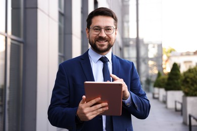 Photo of Successful businessman with tablet near office building