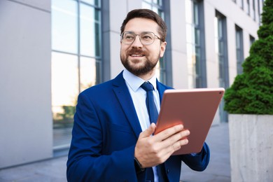 Photo of Successful businessman with tablet near office building