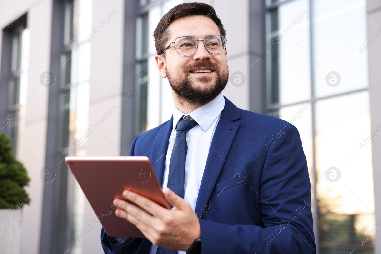 Photo of Successful businessman with tablet near office building