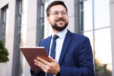 Photo of Successful businessman with tablet near office building