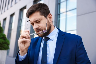 Photo of Tired businessman with glasses outside office building