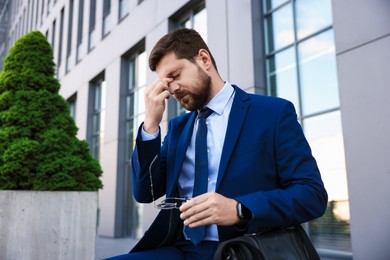 Photo of Tired businessman with glasses outside office building