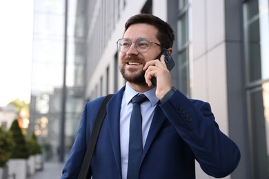Photo of Successful businessman talking on phone near office building