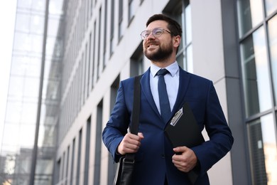 Photo of Successful businessman with clipboard near office building
