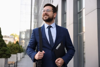 Photo of Successful businessman with clipboard near office building