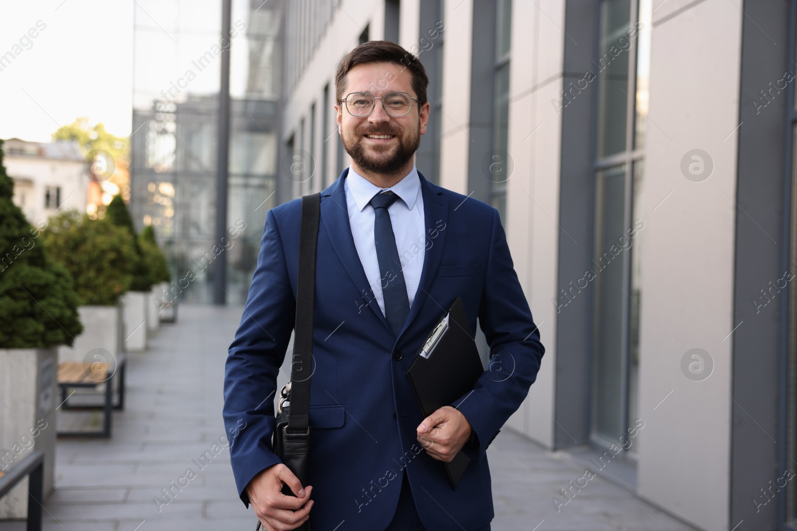 Successful businessman with clipboard near office building Photo of Successful businessman with clipboard near office building