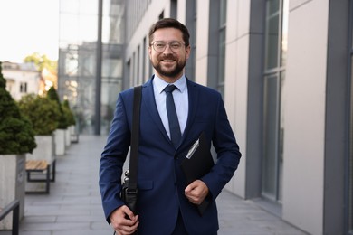 Photo of Successful businessman with clipboard near office building
