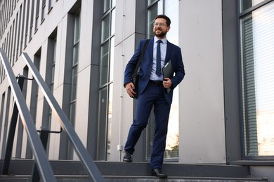 Photo of Successful businessman with clipboard near office building. Space for text