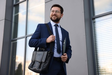 Photo of Successful businessman with clipboard near office building, low angle view