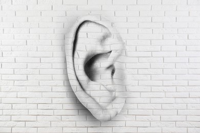 Image of Human ear in white brick wall. Eavesdropping, concept that even walls have ears
