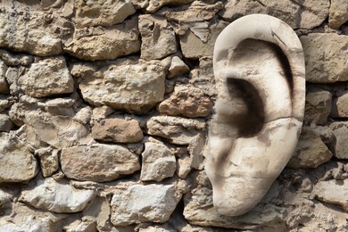 Image of Human ear in old stone wall, space for text. Eavesdropping, concept that even walls have ears