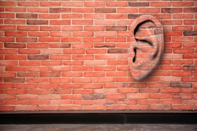Image of Human ear in red brick wall, space for text. Eavesdropping, concept that even walls have ears