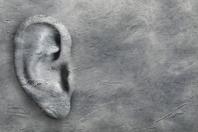 Image of Human ear in grey stone wall, space for text. Eavesdropping, concept that even walls have ears