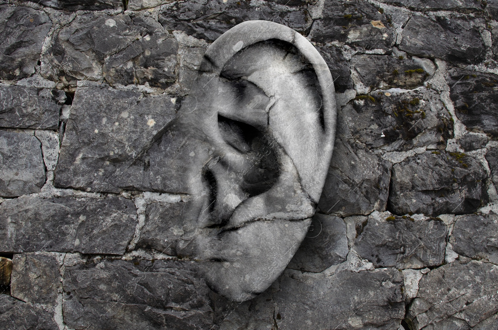 Image of Human ear in grey stone wall. Eavesdropping, concept that even walls have ears