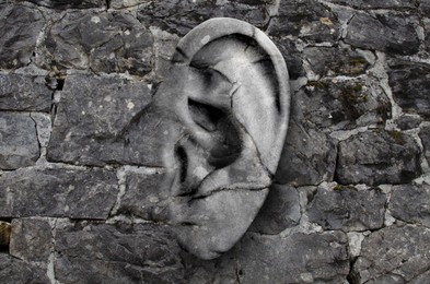 Image of Human ear in grey stone wall. Eavesdropping, concept that even walls have ears