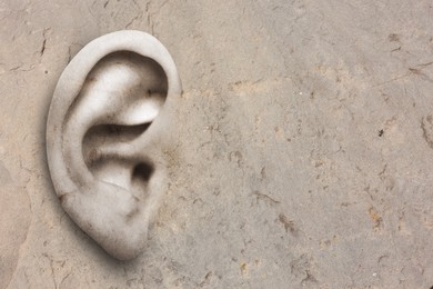 Image of Human ear in grey stone wall, space for text. Eavesdropping, concept that even walls have ears