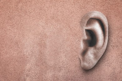 Image of Human ear in pink plaster wall, space for text. Eavesdropping, concept that even walls have ears