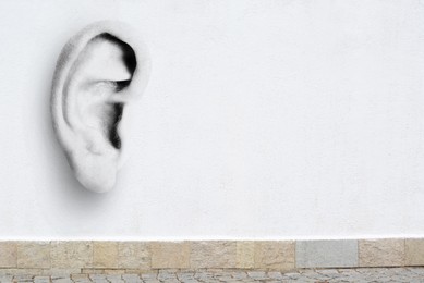 Image of Human ear in white concrete wall, space for text. Eavesdropping, concept that even walls have ears