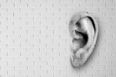 Image of Human ear in white brick wall, space for text. Eavesdropping, concept that even walls have ears