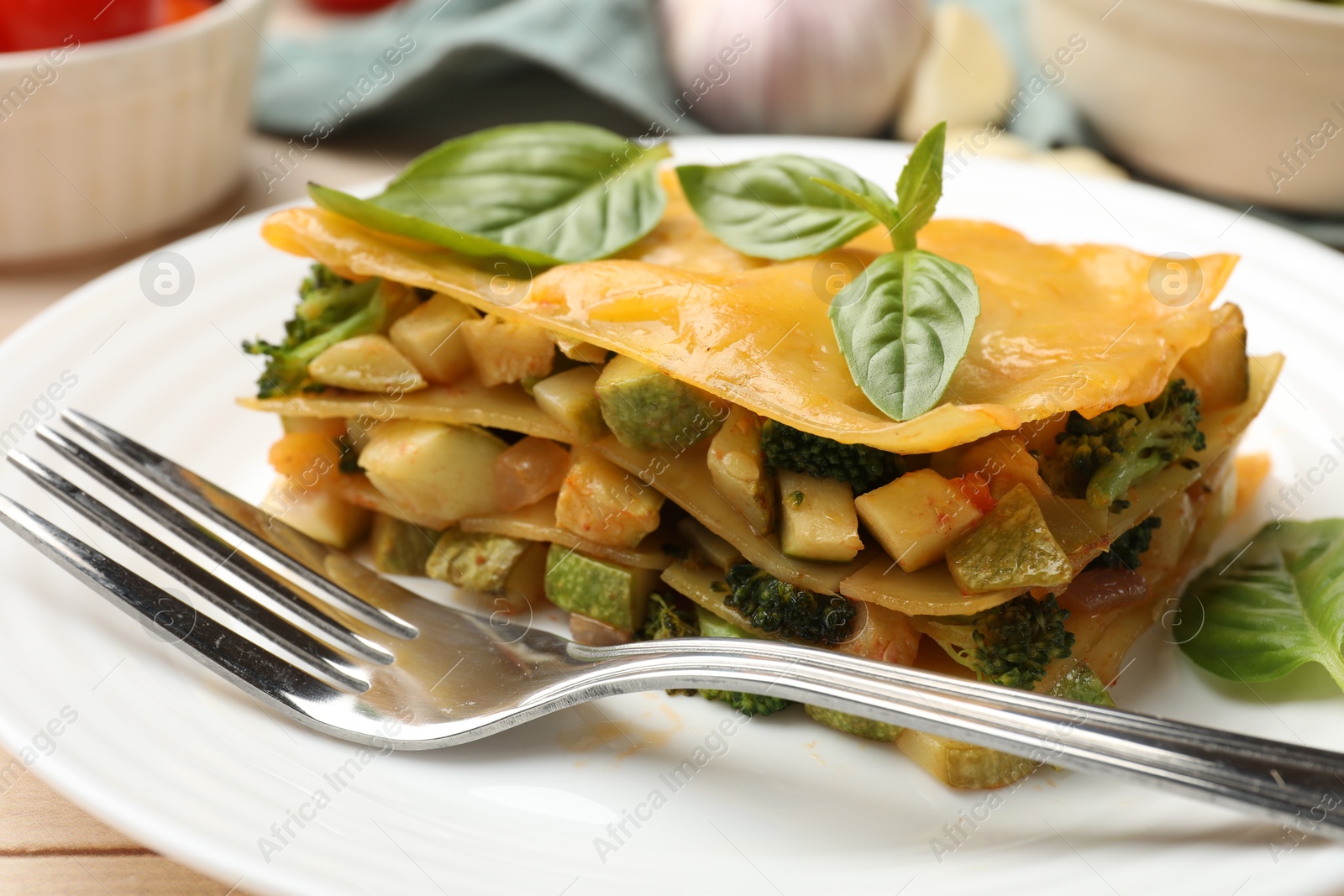 Photo of Piece of tasty vegetarian lasagna served on white wooden table, closeup