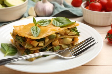 Photo of Piece of tasty vegetarian lasagna served on white wooden table, closeup