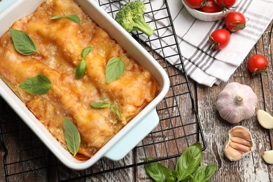 Photo of Tasty vegetarian lasagna in baking dish and ingredients on wooden table, flat lay