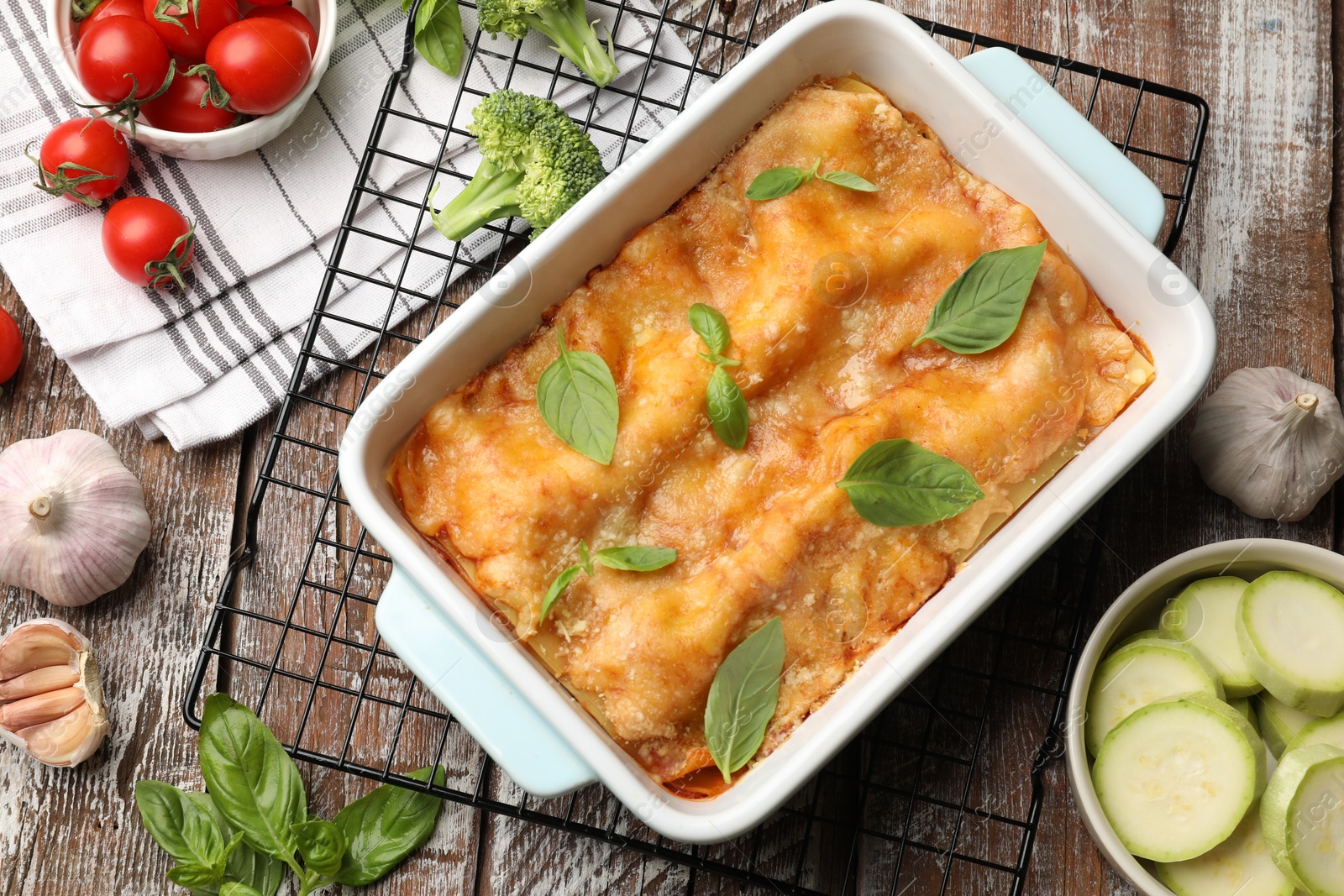 Tasty vegetarian lasagna in baking dish and ingredients on wooden table, flat lay Photo of Tasty vegetarian lasagna in baking dish and ingredients on wooden table, flat lay