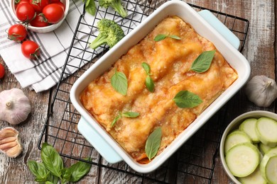 Photo of Tasty vegetarian lasagna in baking dish and ingredients on wooden table, flat lay