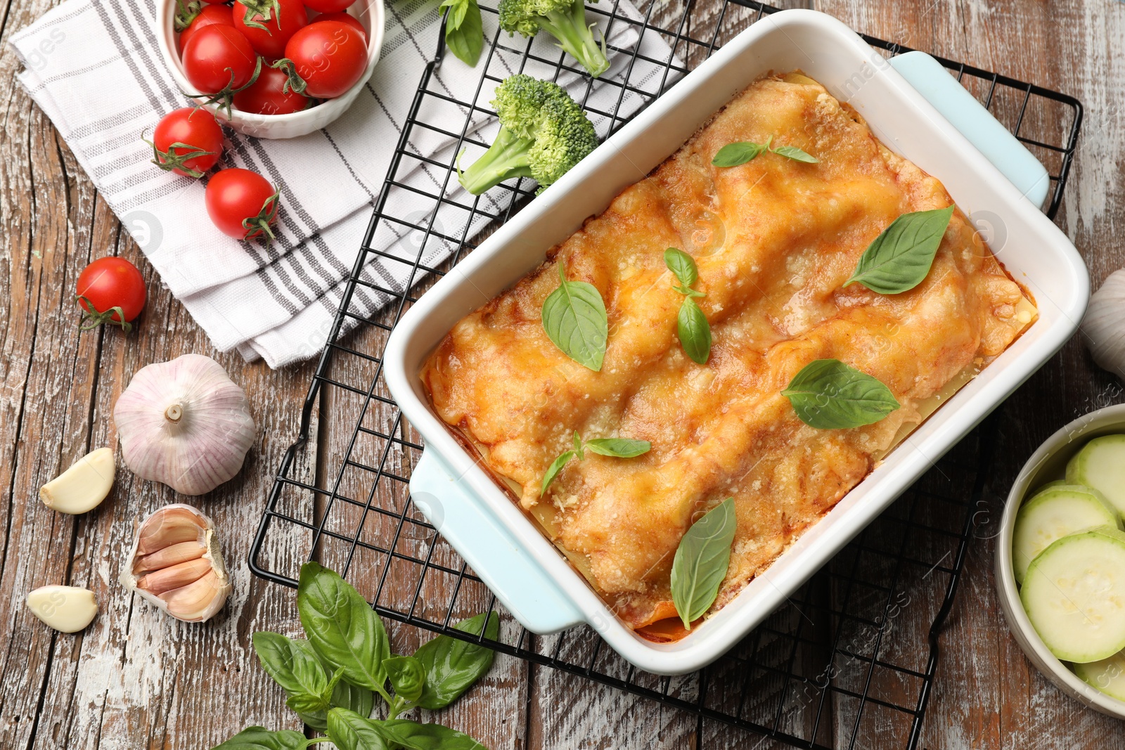 Tasty vegetarian lasagna in baking dish and ingredients on wooden table, flat lay Photo of Tasty vegetarian lasagna in baking dish and ingredients on wooden table, flat lay