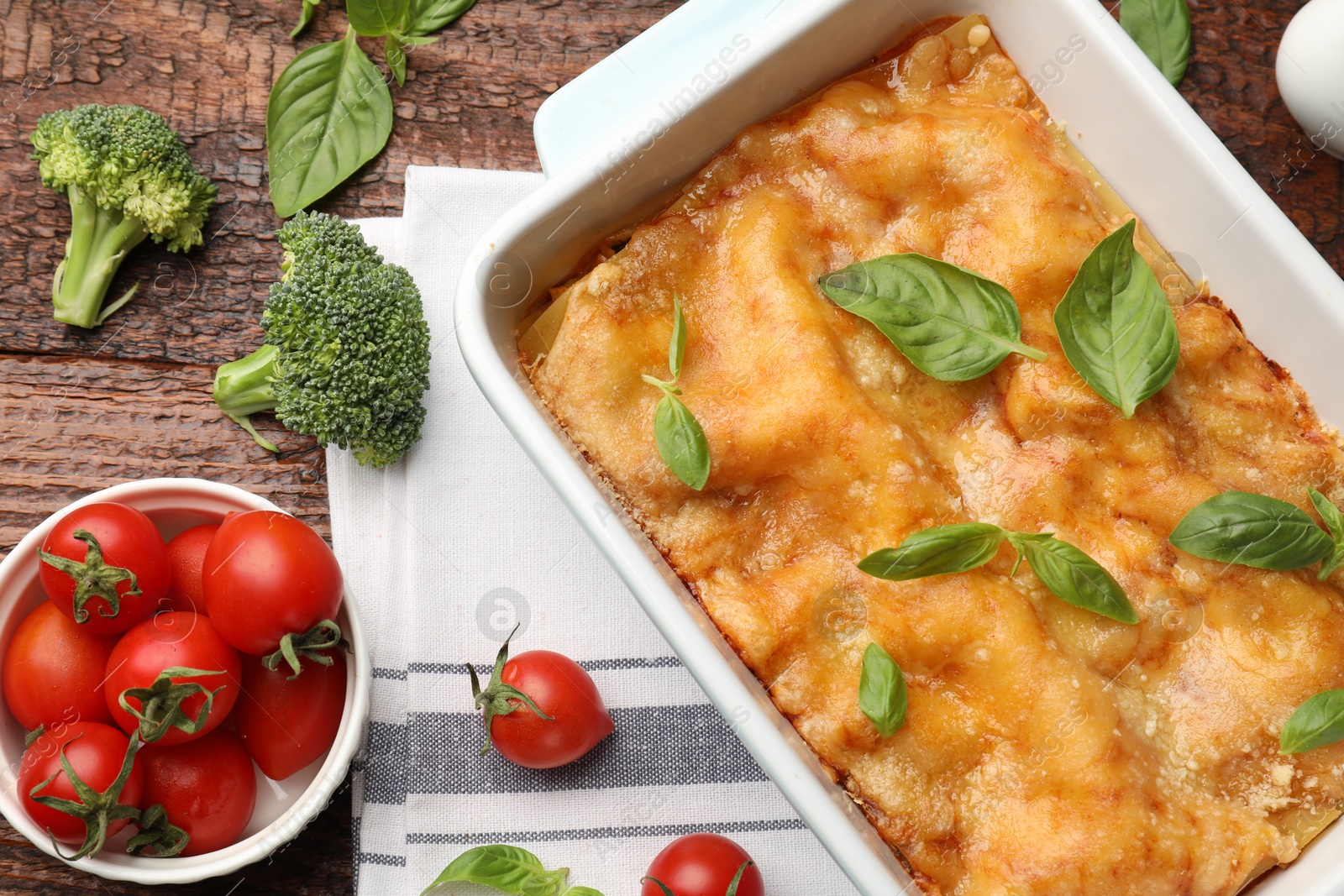 Tasty vegetarian lasagna in baking dish and ingredients on wooden table, flat lay Photo of Tasty vegetarian lasagna in baking dish and ingredients on wooden table, flat lay