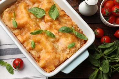 Photo of Tasty vegetarian lasagna in baking dish and ingredients on wooden table, flat lay