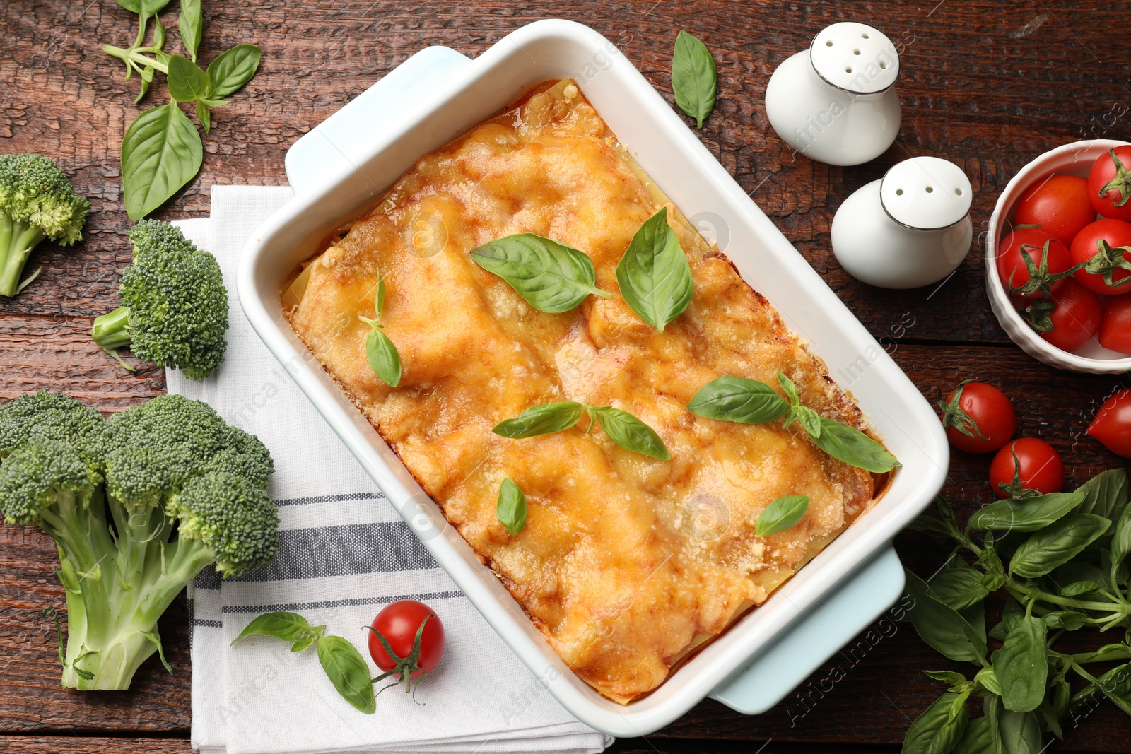 Tasty vegetarian lasagna in baking dish and ingredients on wooden table, flat lay Photo of Tasty vegetarian lasagna in baking dish and ingredients on wooden table, flat lay