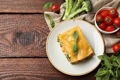 Photo of Piece of tasty vegetarian lasagna and ingredients on wooden table, flat lay. Space for text