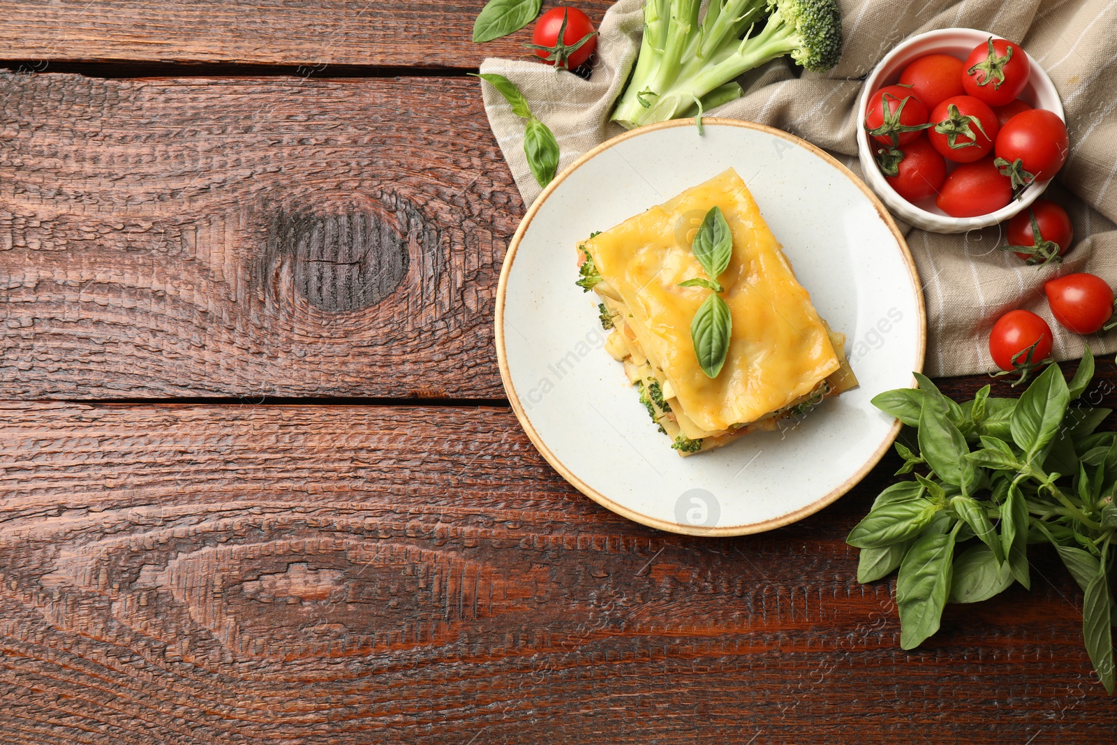 Photo of Piece of tasty vegetarian lasagna and ingredients on wooden table, flat lay. Space for text