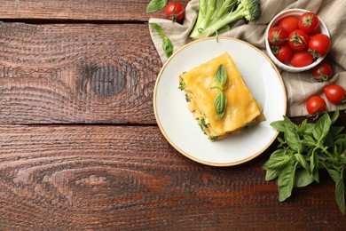 Photo of Piece of tasty vegetarian lasagna and ingredients on wooden table, flat lay. Space for text