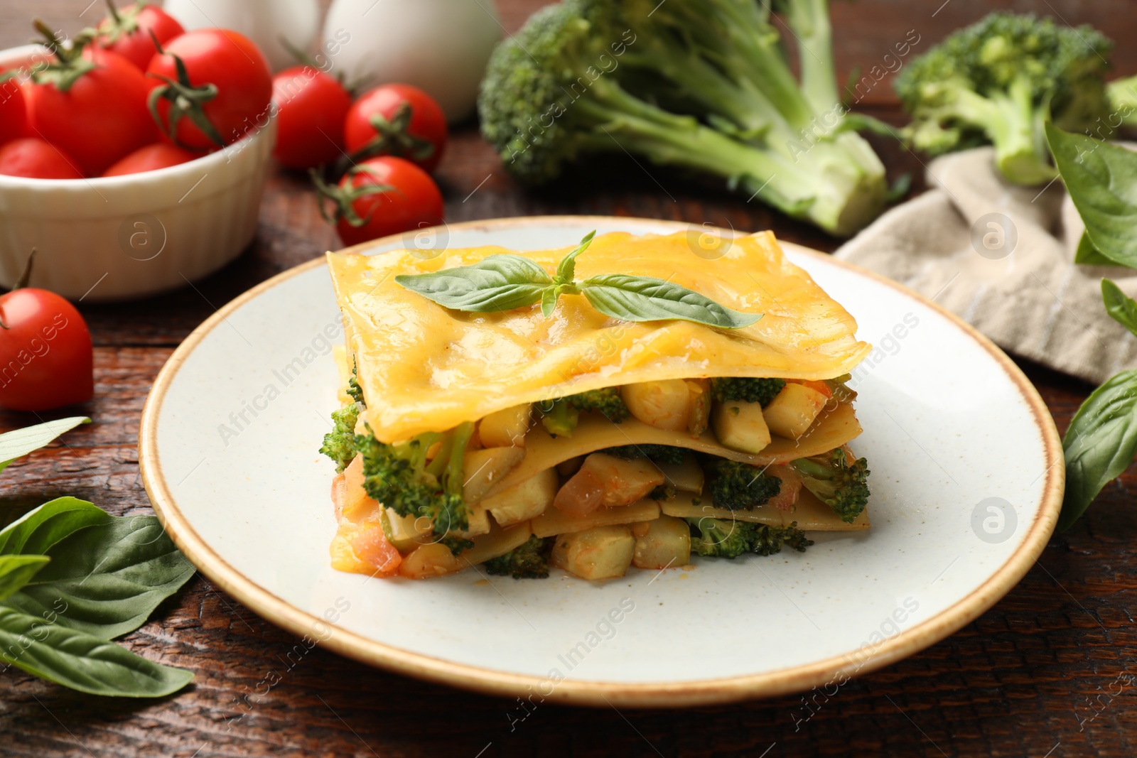 Piece of tasty vegetarian lasagna and ingredients on wooden table, closeup Photo of Piece of tasty vegetarian lasagna and ingredients on wooden table, closeup