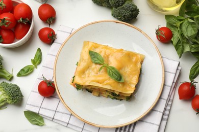 Photo of Piece of tasty vegetarian lasagna and ingredients on white table, flat lay