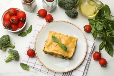 Photo of Piece of tasty vegetarian lasagna and ingredients on white table, flat lay