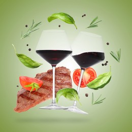 Image of Red wine in glasses, grilled beef steak, tomatoes and spices falling on light green gradient background