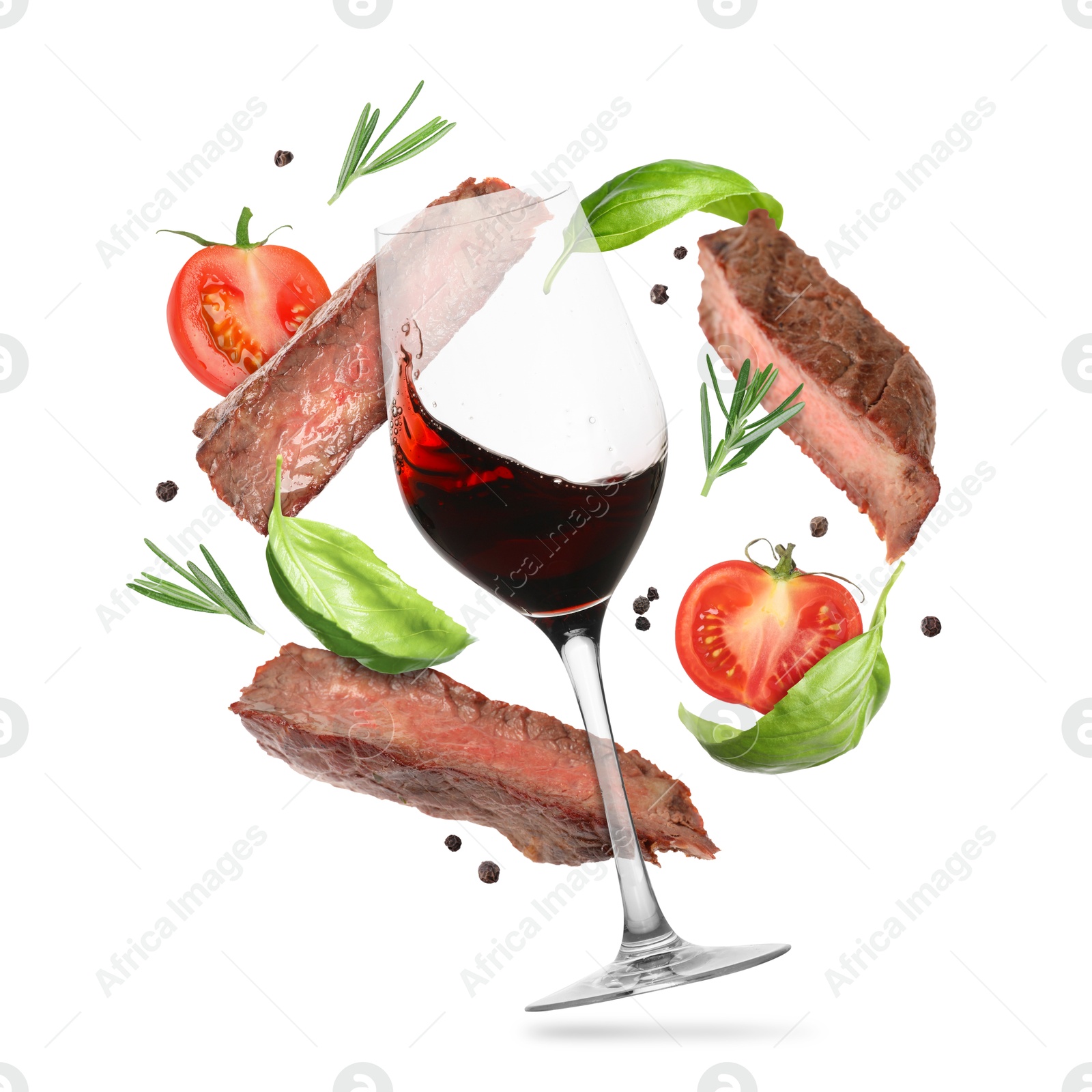 Red wine in glass, grilled beef meat, tomatoes and spices falling on white background Image of Red wine in glass, grilled beef meat, tomatoes and spices falling on white background