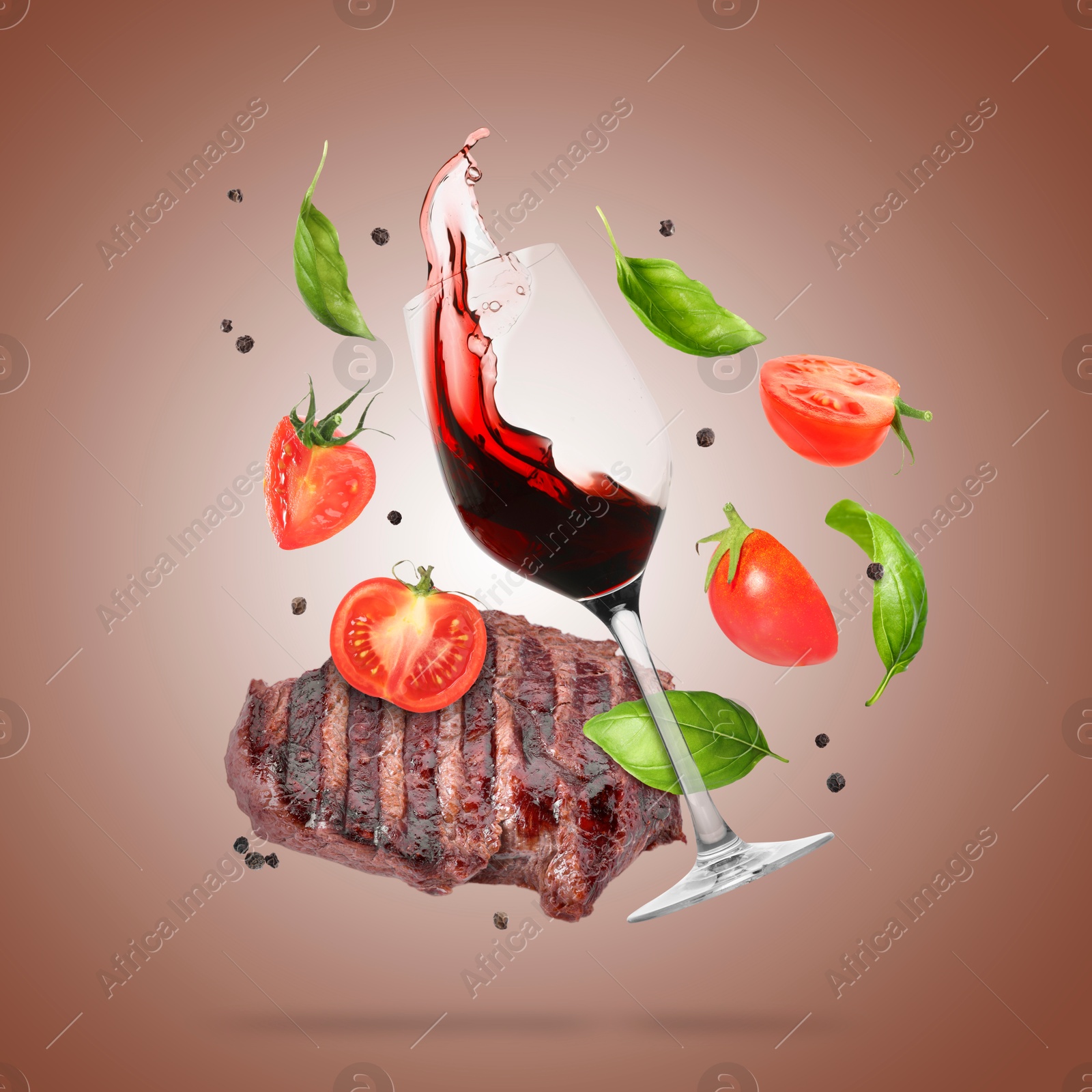 Red wine in glass, grilled beef steak, tomatoes and spices falling on brown gradient background Image of Red wine in glass, grilled beef steak, tomatoes and spices falling on brown gradient background
