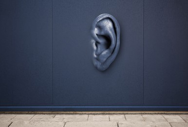 Image of Human ear in blue wall. Eavesdropping, concept that even walls have ears