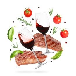 Image of Red wine in glasses, grilled beef steaks, tomatoes and spices falling on white background