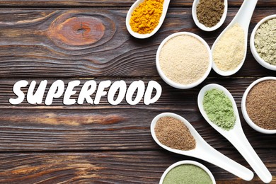 Image of Superfood. Different powders in bowls and spoons on wooden table, flat lay