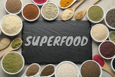 Image of Different superfoods and slate board on grey table, flat lay