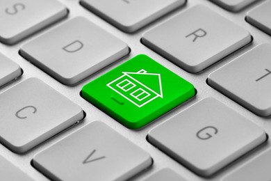 Image of Online accommodation search. Button with house icon on computer keyboard, closeup
