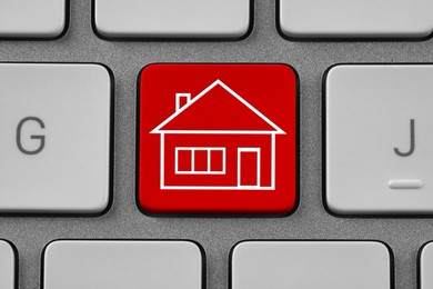 Image of Online accommodation search. Button with house icon on computer keyboard, closeup