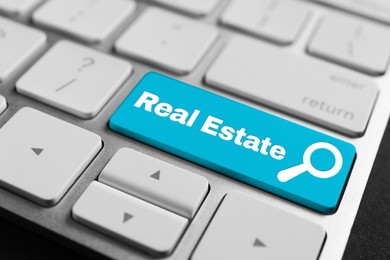 Image of Online accommodation search. Button with magnifying glass icon and words Real Estate on computer keyboard, closeup