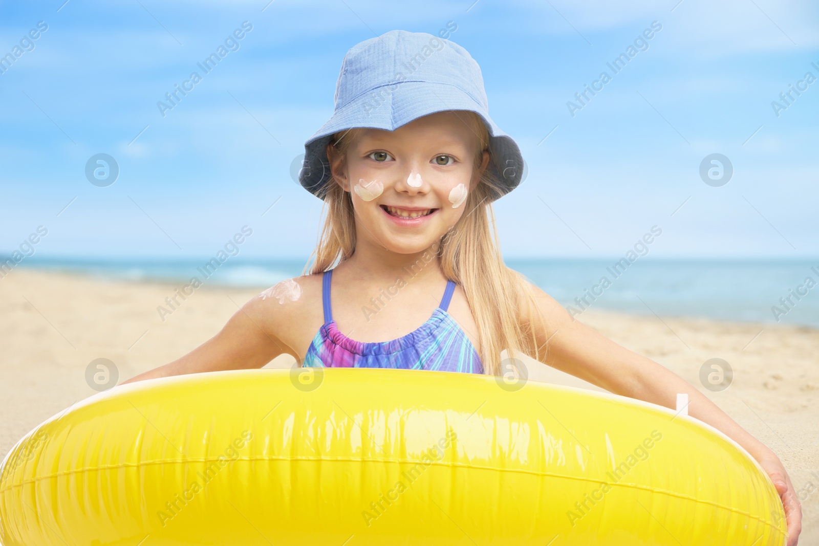 Cute little girl with sunscreen on her skin holding inflatable ring at beach. Sun protection while outdoor recreation in summer Image of Cute little girl with sunscreen on her skin holding inflatable ring at beach. Sun protection while outdoor recreation in summer