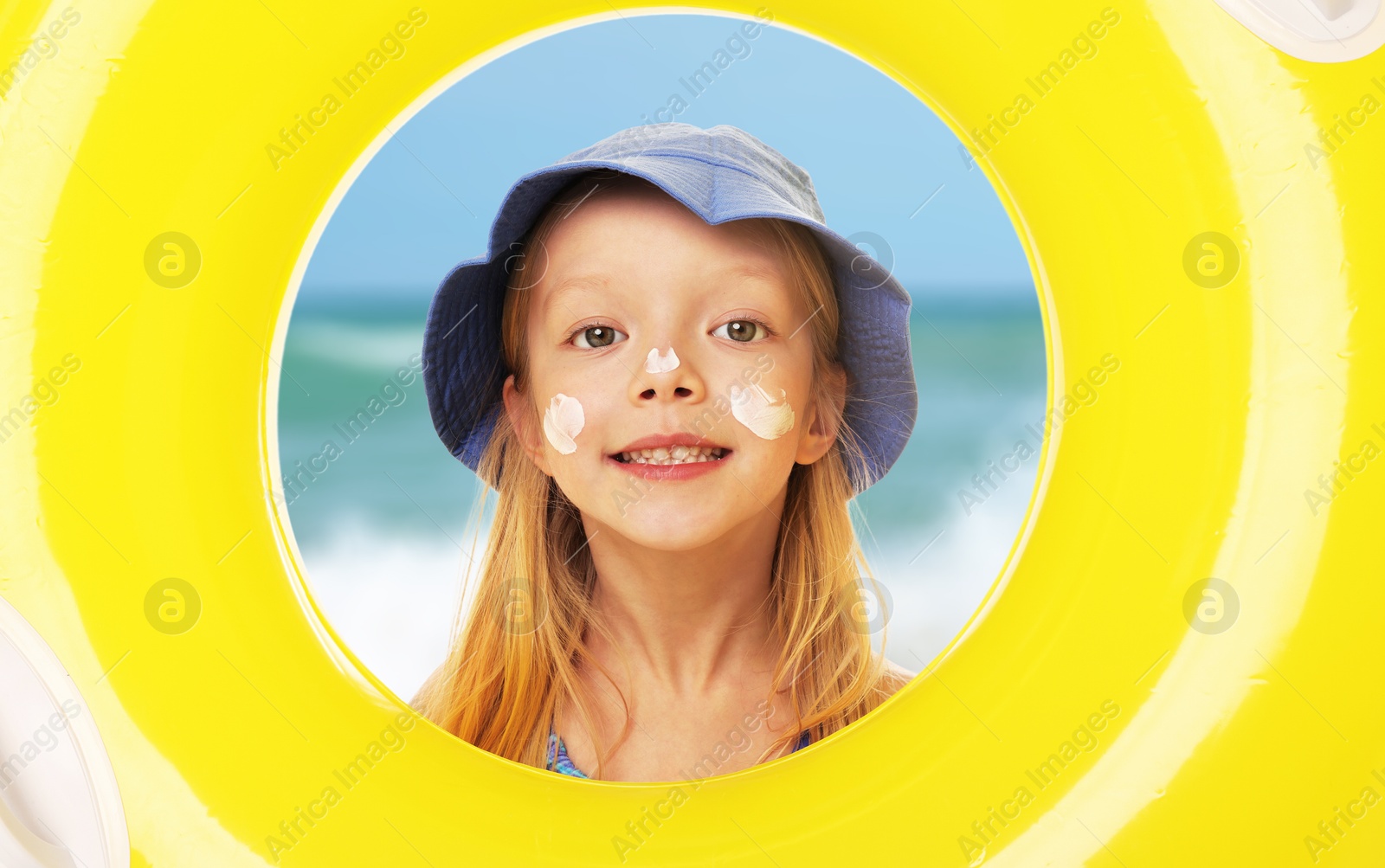 Cute little girl with sunscreen on her face looking through hole of inflatable ring at beach. Sun protection while outdoor recreation in summer Image of Cute little girl with sunscreen on her face looking through hole of inflatable ring at beach. Sun protection while outdoor recreation in summer
